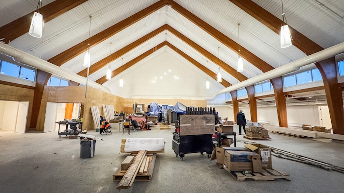 Vue d'ensemble sur la nef d'une église en pleine rénovation. Des poutres de bois et des lampadaires ont été préservé, et beaucoup de matériel de construction occupent l'espace.