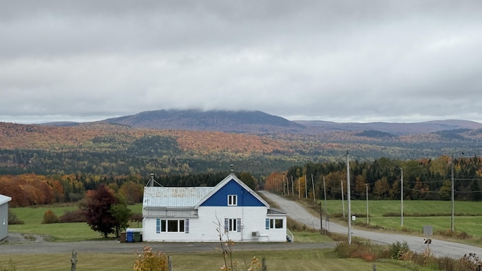Une maison blanche dans le paysage automnal et montagneux de Saint-Apolline-de-Patton.