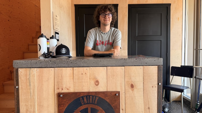 Un jeune homme derrière un comptoir d'accueil. 