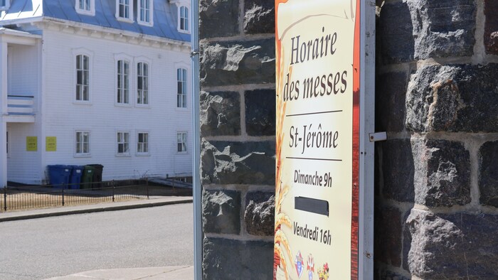Une pancarte indiquant l'horaire des messes devant l'église.