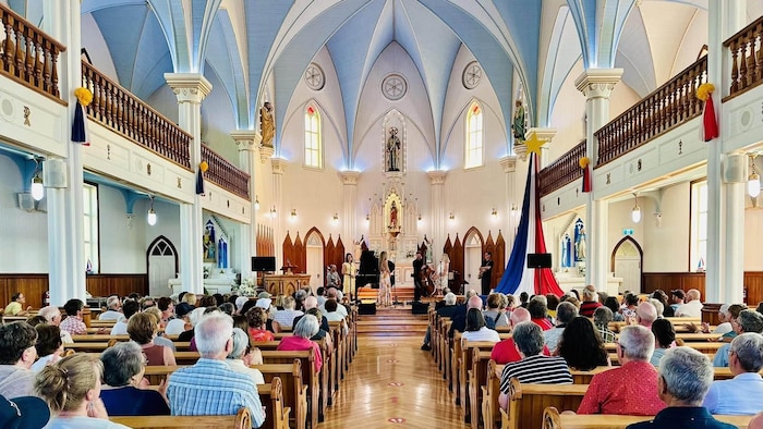 L'intérieur de l'église de Saint-Simon, remplie de spectateurs assis sur les bancs.