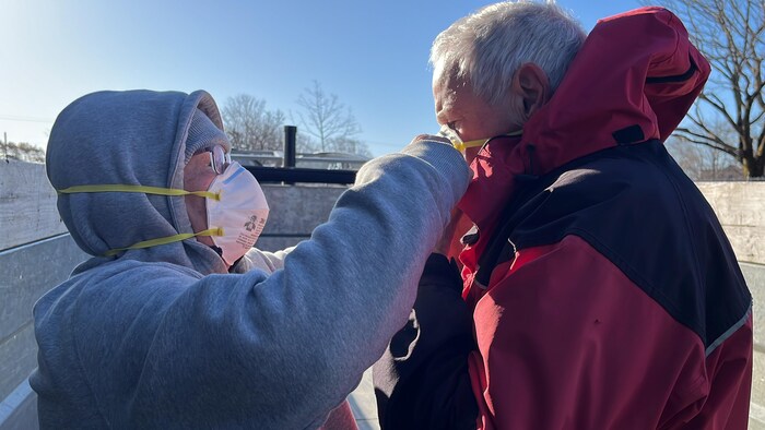 Une bénévole fixe un masque N-95 sur le visage d'un homme.