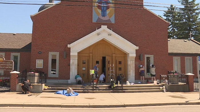 Des gens frottent la façade extérieure d'une église.