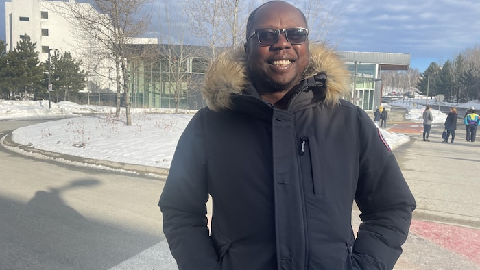 Ehouman Charles Coulibaly souriant à l’extérieur de l’Université.