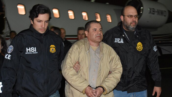 Joaquin « El Chapo » Guzman avec des agents à ses côtés, devant un avion.
