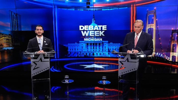 Abdul El-Sayed et Mike Rogers se tiennent chacun derrière un pupitre transparent sur un plateau de télévision.