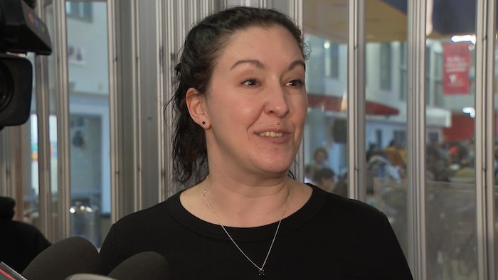 Une femme en conférence de presse à l'intérieur d'un immeuble.