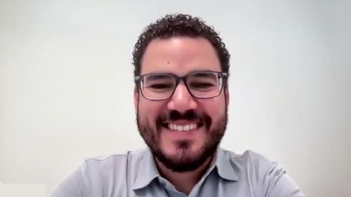 Un homme souriant regarde la caméra lors d'une rencontre virtuelle.
