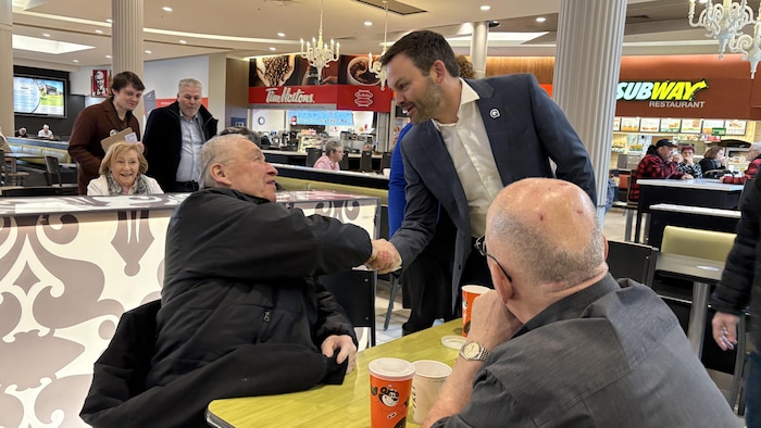 un homme serre la main d'un autre dans un centre commercial
