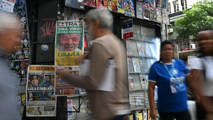 Des personnes marchent devant une boutique de journaux au Brésil.