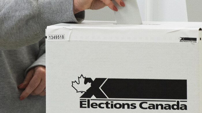 Une femme déposant son bulletin de vote dans une boîte.