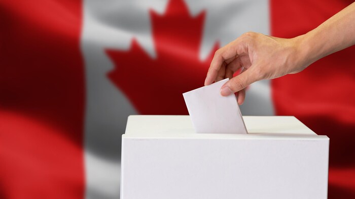 Une main dépose un bulletin de vote dans une urne.