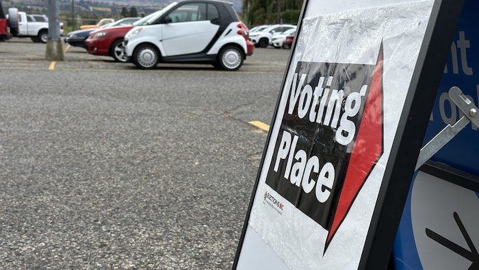 Un panneau placé dans un parc de stationnement indique un bureau de vote.