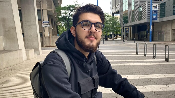 Mohammad Zohour assis sur des marches devant son université.