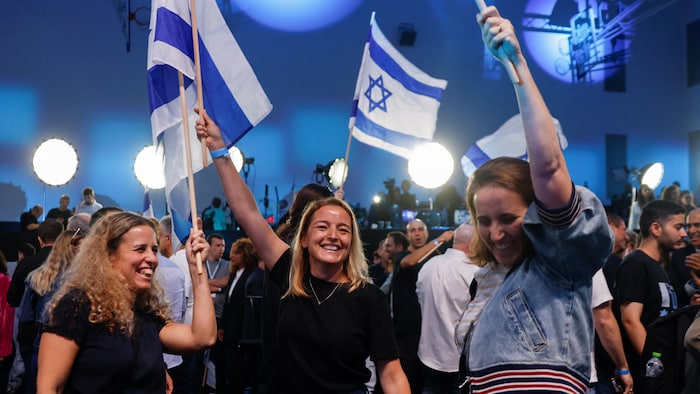 Des femmes sourient et brandissent des drapeaux d'Israël.