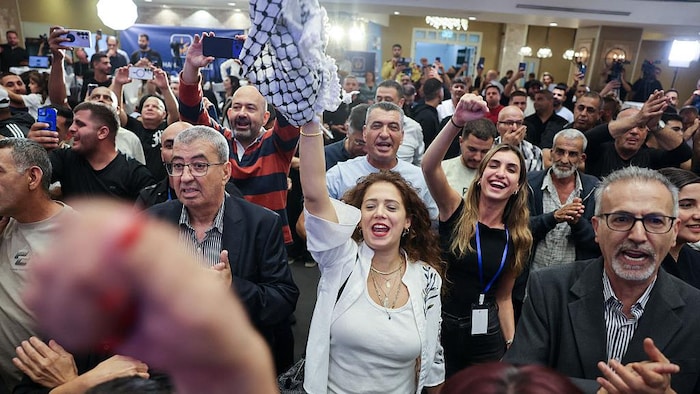 Des gens applaudissent et une femme brandit un keffieh.