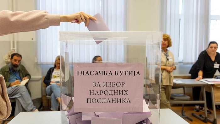 Une électrice dépose son bulletin de vote dans un bureau de vote à Belgrade, le 25 octobre 2026, à l'occasion des élections législatives anticipées en Serbie.