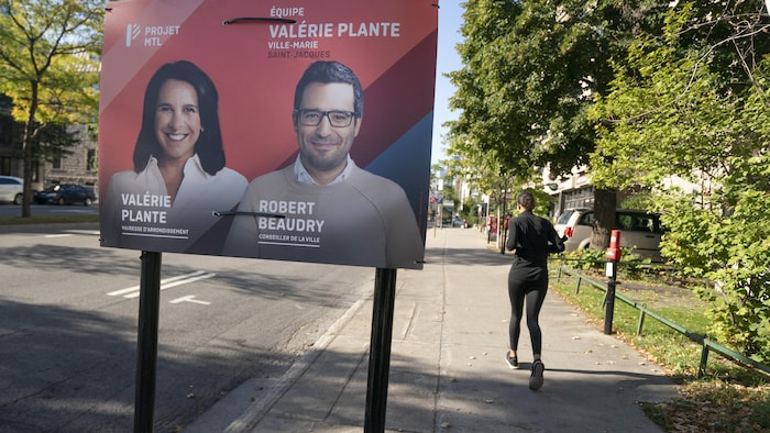 Une joggeuse passe près d'une pancarte électorale de Projet Montréal.