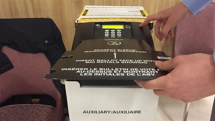 Insertion d'un bulletin de vote dans une tabulatrice au Nouveau-Brunswick.