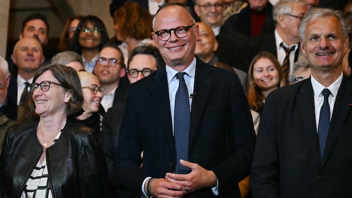 Un homme sourit au milieu d'une foule.