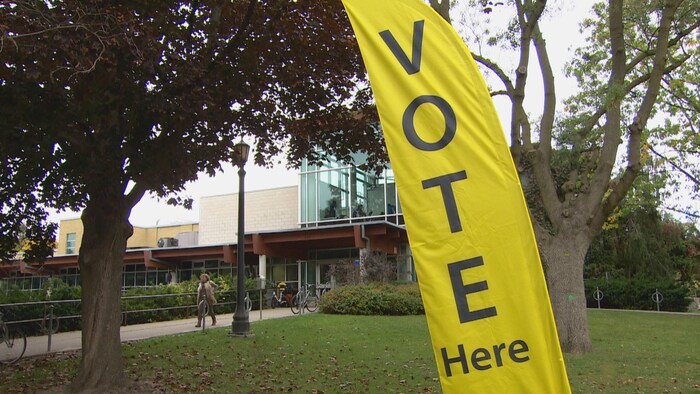 Un panneau jaune qui indique l'emplacement d'un bureau de vote dans un centre communautaire de Toronto.