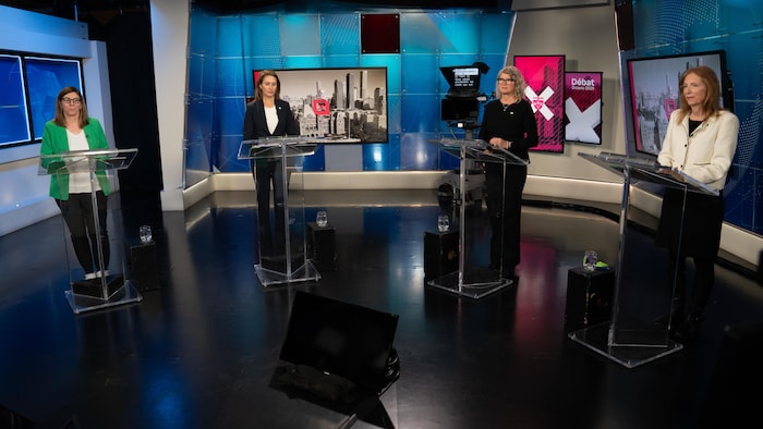 Quatre personnes sont debout face à des pupitres.