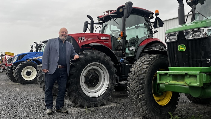 Stéphane Bisaillon devant des tracteurs.