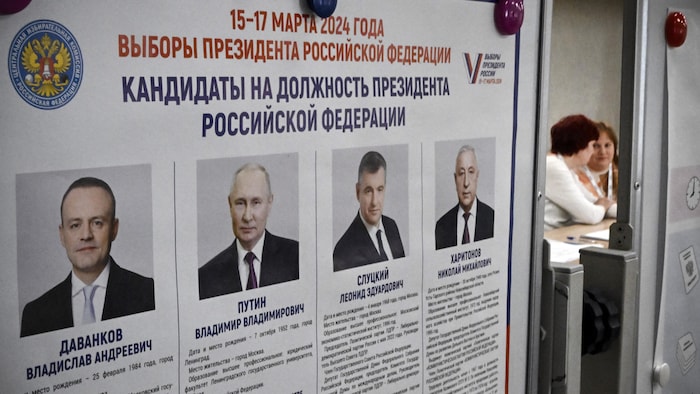 İki kadın, Rusya başkanlık seçimi adaylarıyla bir posterin yanında sohbet ediyor.