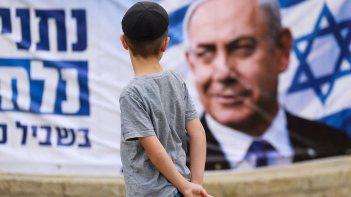 Un garçon regarde une grande affiche de Benyamin Nétanyahou.