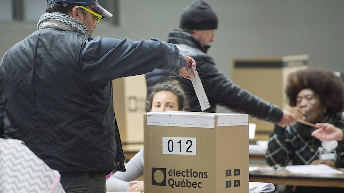 Un électeur glisse son bulletin de vote dans une boîte prévue à cet effet.