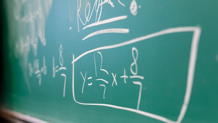 Un tableau sur lequel des équations mathématiques sont écrites à la craie.