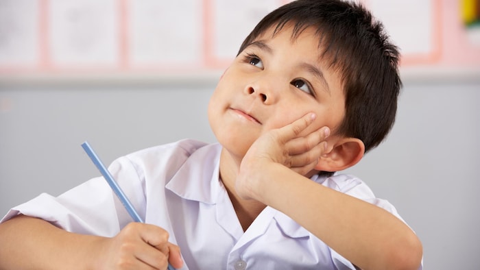 Un jeune étudiant du primaire rêvassant en classe.