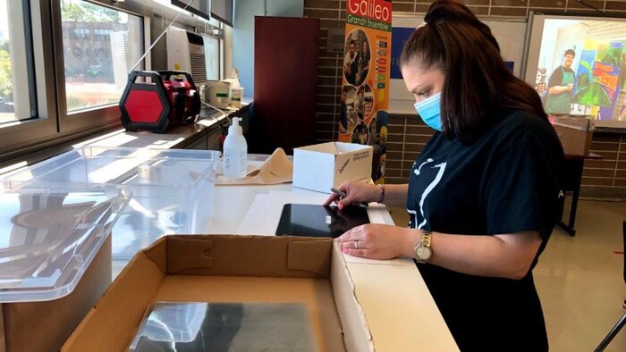 Une jeune femme fabrique une visière.