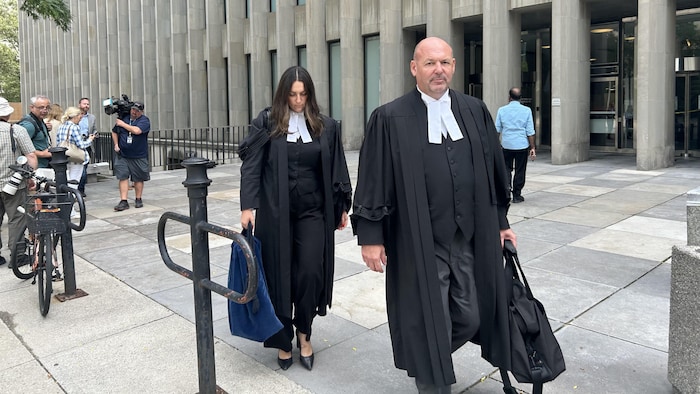 Peter Brauti et une femme en toges noires qui marche sur un trottoir.