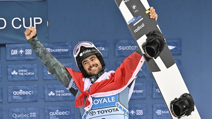 Eliot Grondin of Sainte-Marie Que. celebrates his third place finish, at the FIS snowboard cross world cup event at Mont-Sainte-Anne resort in Beaupre, Que., Sunday, March 26, 2023. Grondin also placed third in the FIS overall season title. THE CANADIAN PRESS/Jacques Boissinot