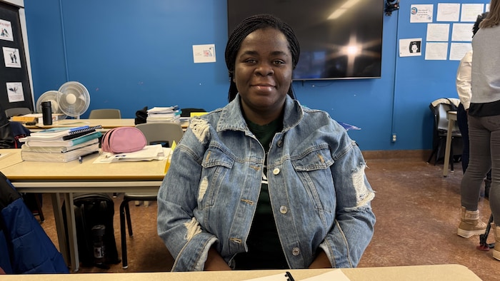 Une femme assises derrière une table pose pour la photo. 