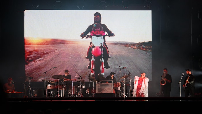 A woman sings on stage with musicians. elisapie's "ultimate dream" who became