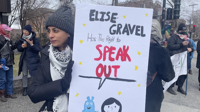 Une personne tient une pancarte qui porte la mention en anglais : «Elise a le droit de s'exprimer».