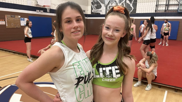 Les deux cheerleaders posent pour la caméra dans un gymnase.