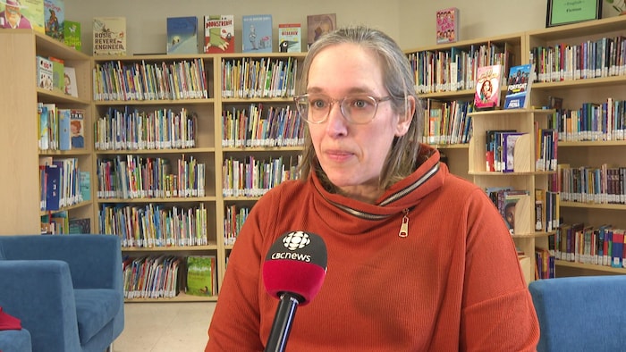 Elizabeth Blake interviewée devant une bibliothèque.