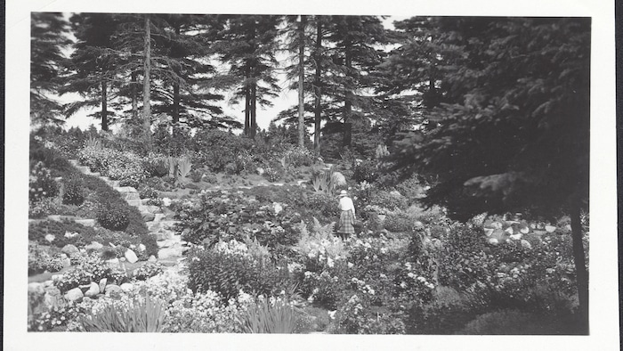 Une photo en noir et blanc montre le Jardin du ruisseau et Elsie Reford de dos.