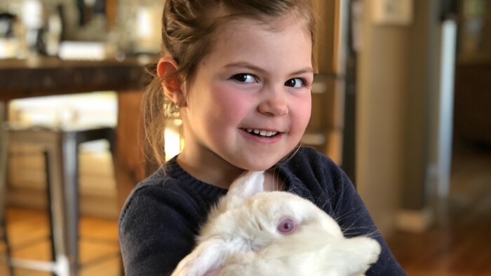 Élyse tient dans ses bras son gros lapin blanc Pita!