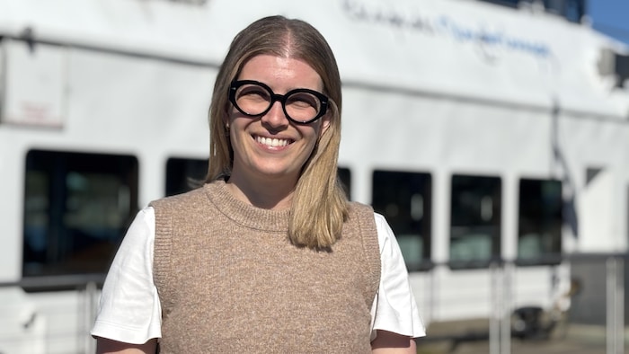 Elyse L'Espérance se tient devant le bateau Le Grand Cru.