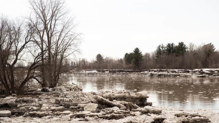 Des blocs de glace se trouvent sur la rive d’une rivière.