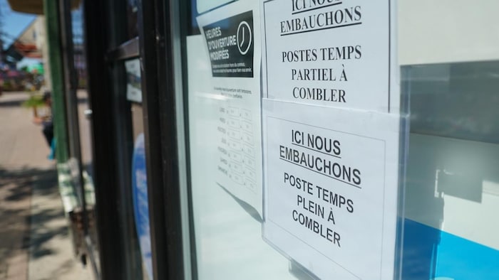Des affiches « Nous embauchons » sur la porte d'un commerce.