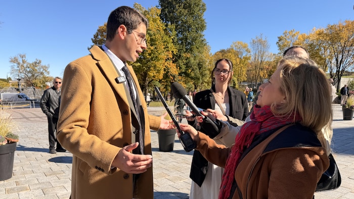 Un homme parle devant les micros tendus des journalistes.