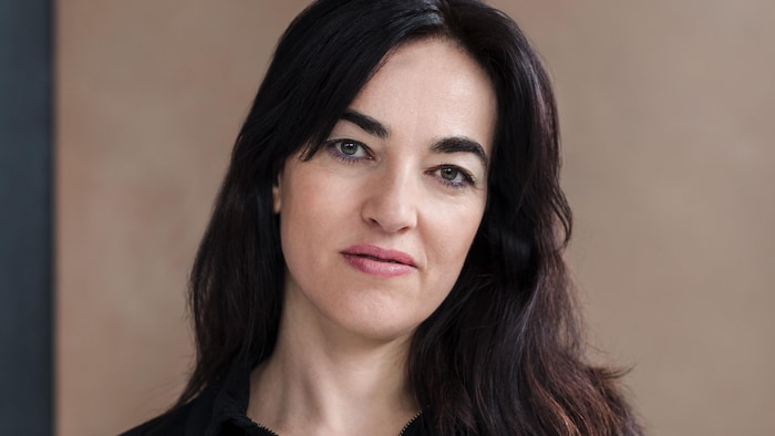 Émilie Monnet regarde directement la caméra, en souriant légèrement.