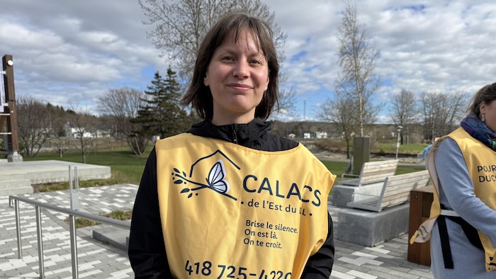 Une femme souriante avec un dossard du CALACS se tient devant l'objectif.