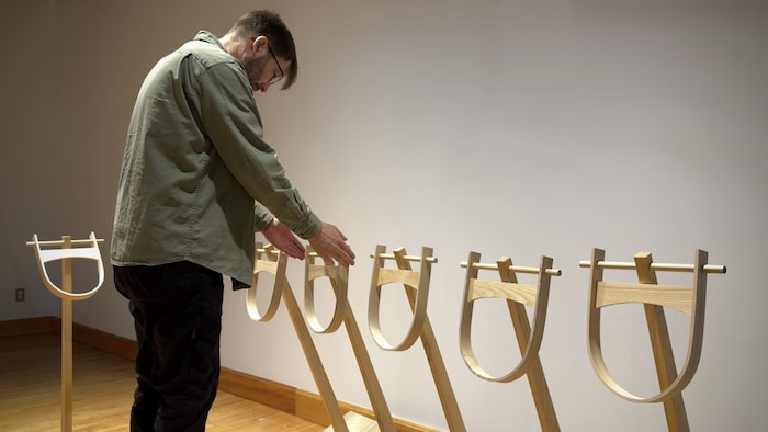 L'artiste Emmanuel Guy bouge une sculpture dans une salle d'exposition.