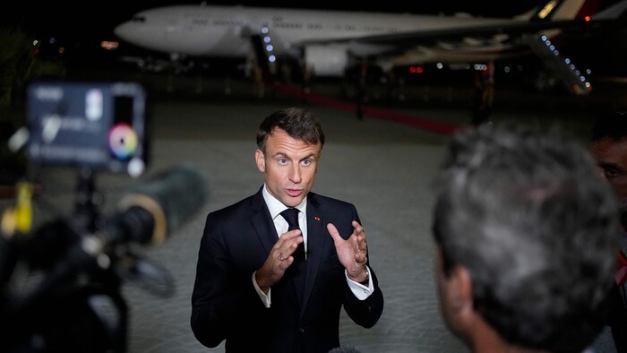 Emmanuel Macron s'entretient avec des journalistes sur le tarmac d'un aéroport.